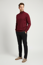 Male model wearing the Lux dark-red mock-neck sweater in a three-quarter view