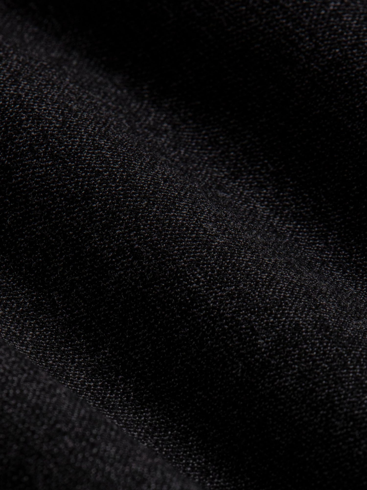 Close-up of dark grey chino fabric showing fine texture and premium woven finish.