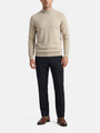 Man wearing a beige mock-neck pullover styled with dark trousers and brown loafers.