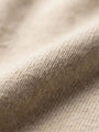 Close-up of beige pullover knit fabric showing soft, textured material detail.