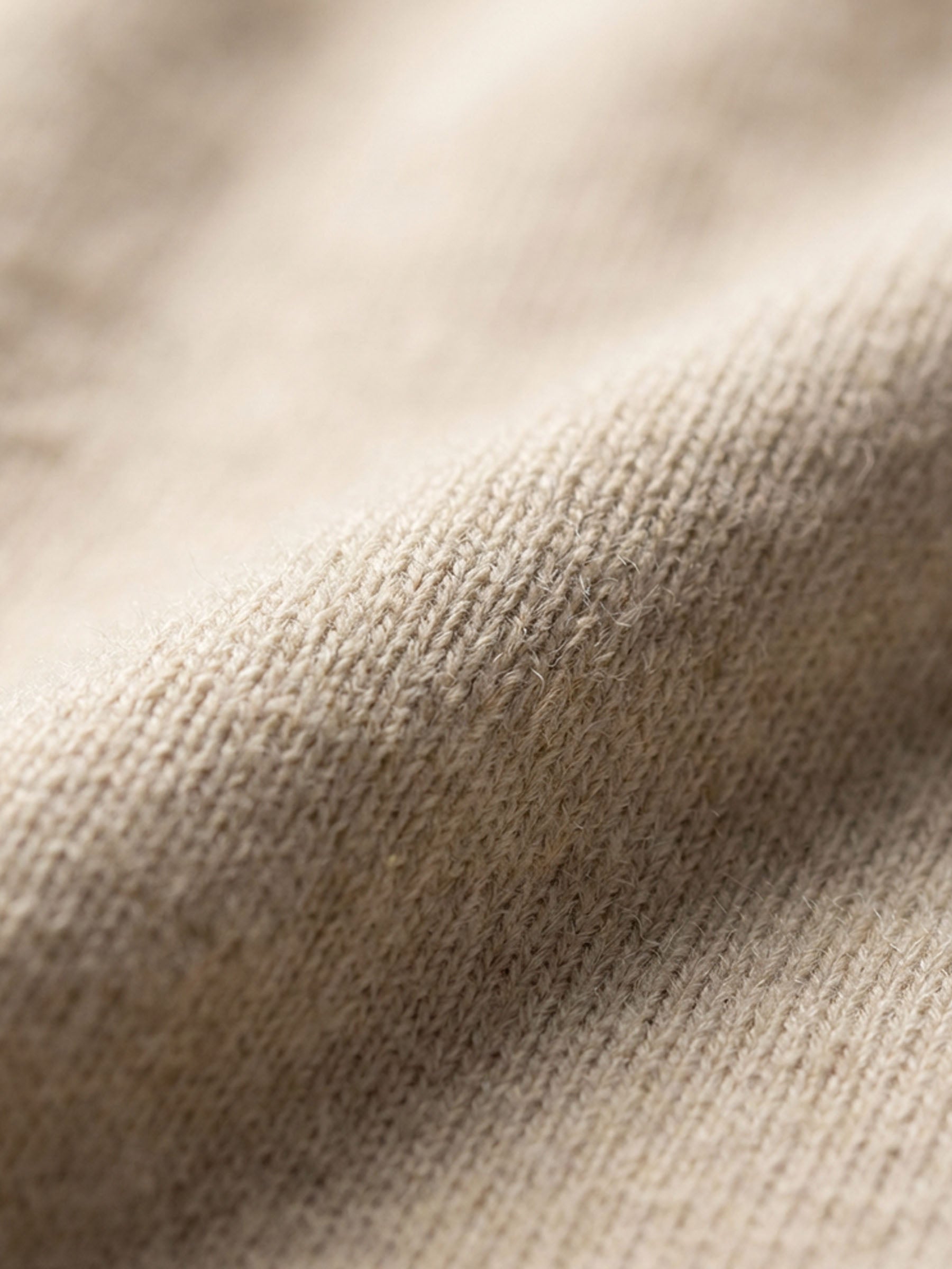 Close-up of beige pullover knit fabric showing soft, textured material detail.