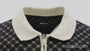 Black and beige patterned polo shirt with zipper collar turning under studio light, showcasing fabric texture and premium fit – Wam Denim.