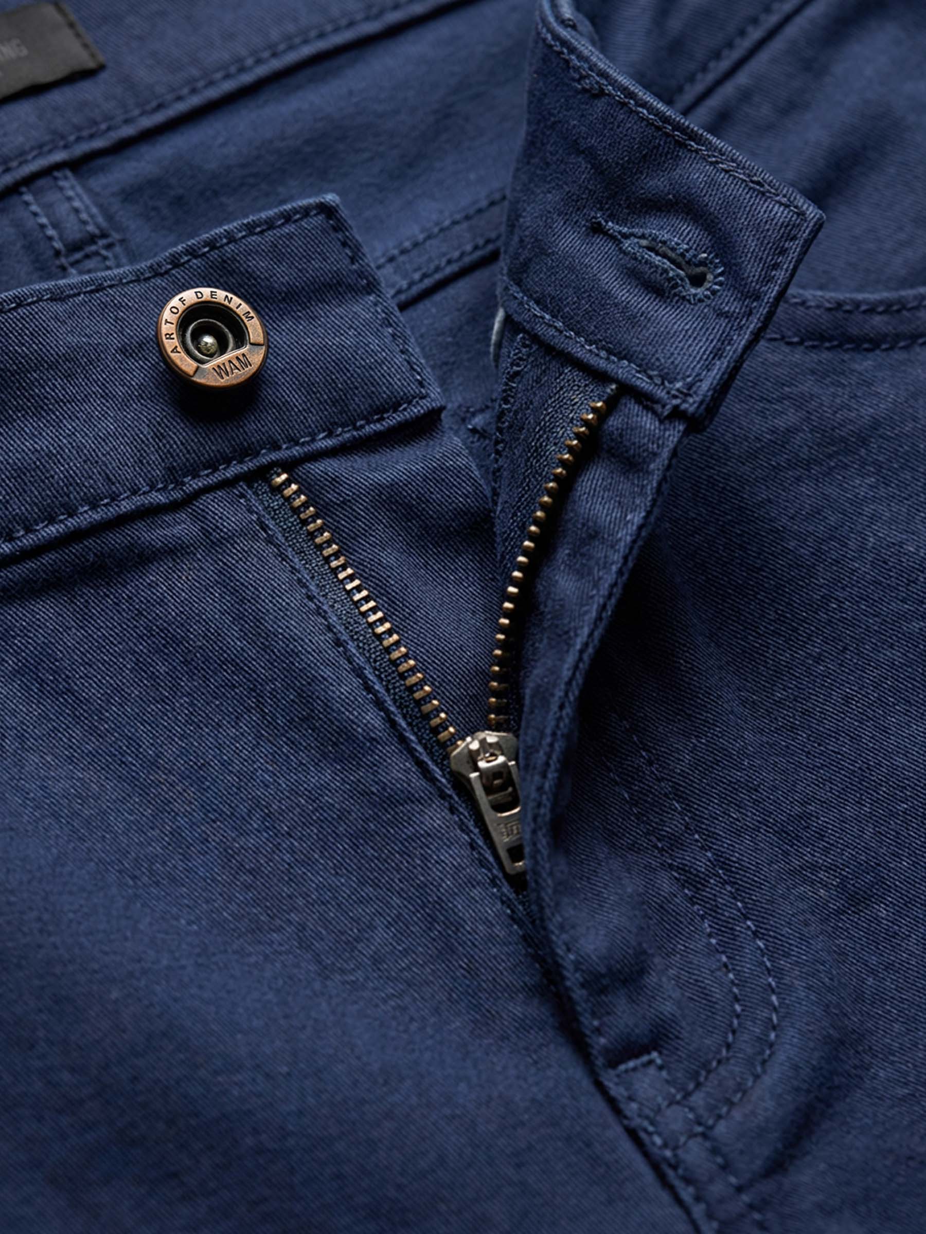 Detail of navy denim jeans with branded button, zipper, and reinforced stitching