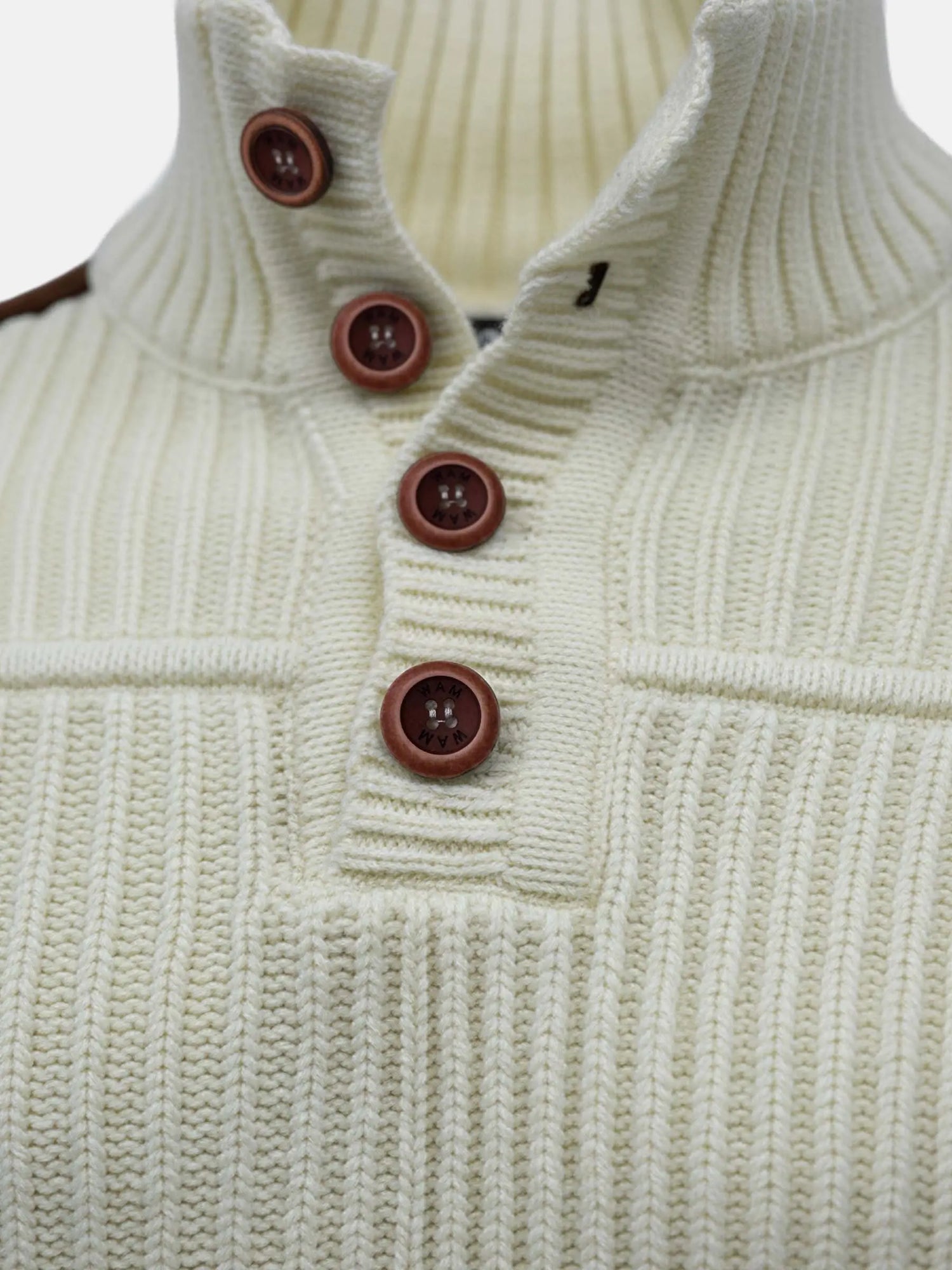 Close-up of off-white knit sweater showing ribbed texture and brown button-neck detail.
