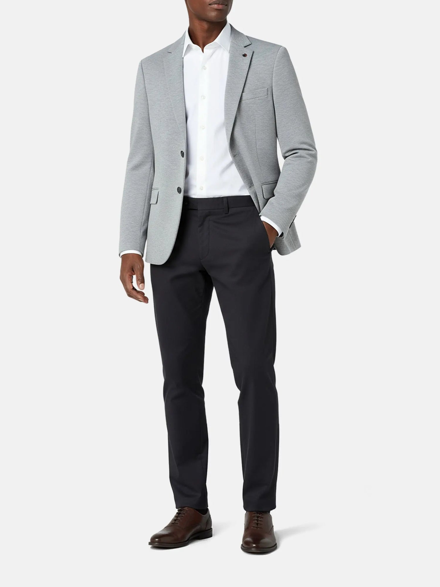 Model wearing light grey blazer with white shirt and black trousers, smart casual outfit.