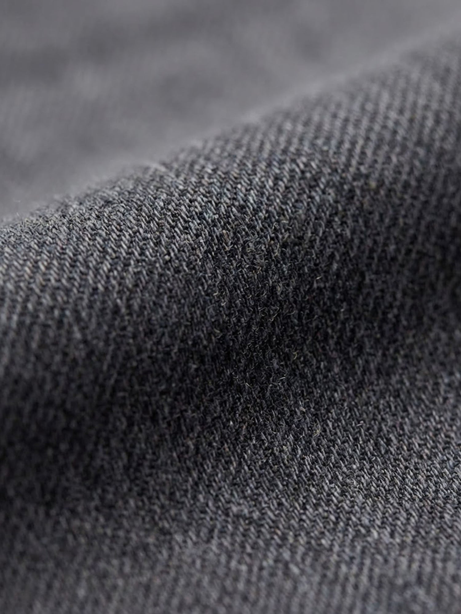 Close-up of grey denim fabric texture with fine weave detail.
